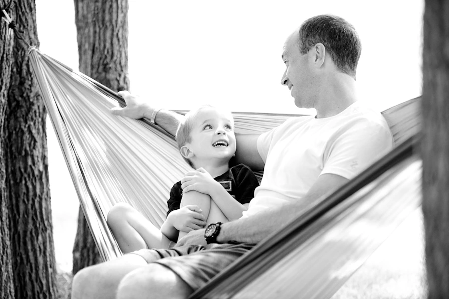 father talking to son in hammock