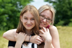 Mother with arms around pre-teen daughter