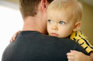 Father holding young son who is resting on his shoulder